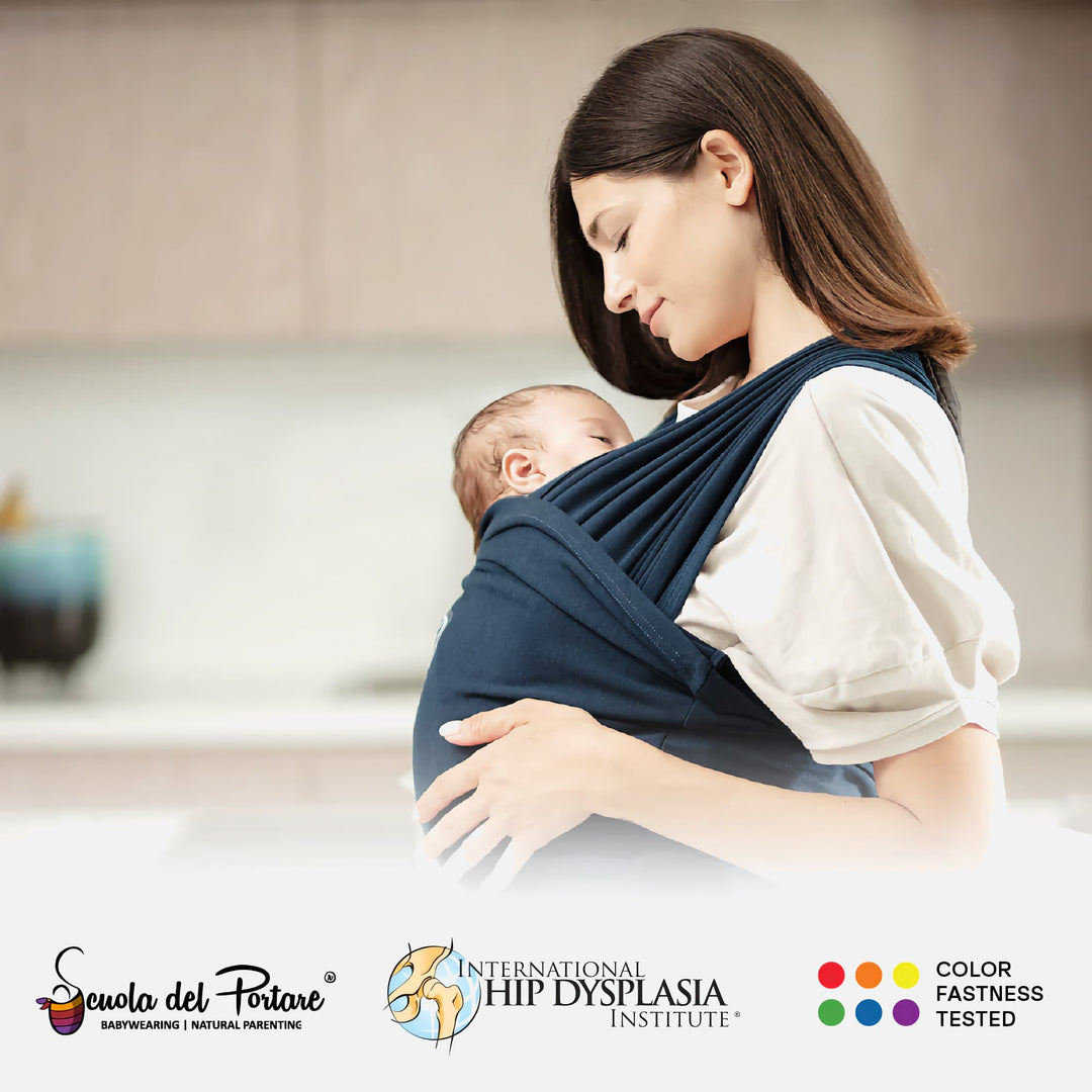 Mother cradling baby in dark blue Koala Cuddle Band 2, shown in a home setting with certified safety logos