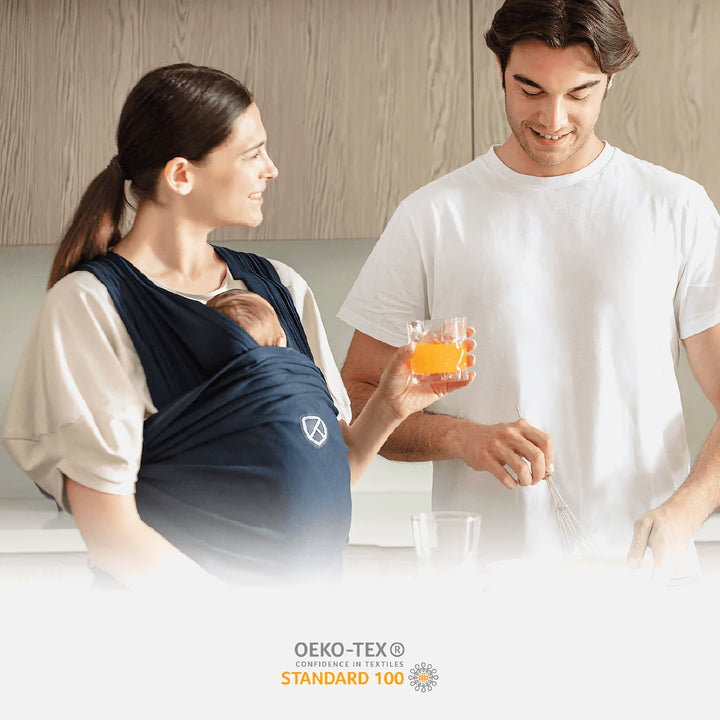 Koala Cuddle Band 2 in dark blue worn by mom holding baby in kitchen, OEKO-TEX certified, relaxed family lifestyle scene
