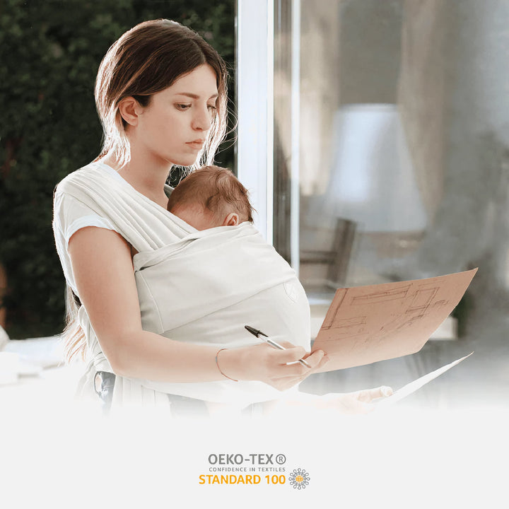 Mother wearing the Koala Cuddle Band 2 baby sling carrier while working, with OEKO-TEX Standard 100 certification for safe, toxin-free fabric.