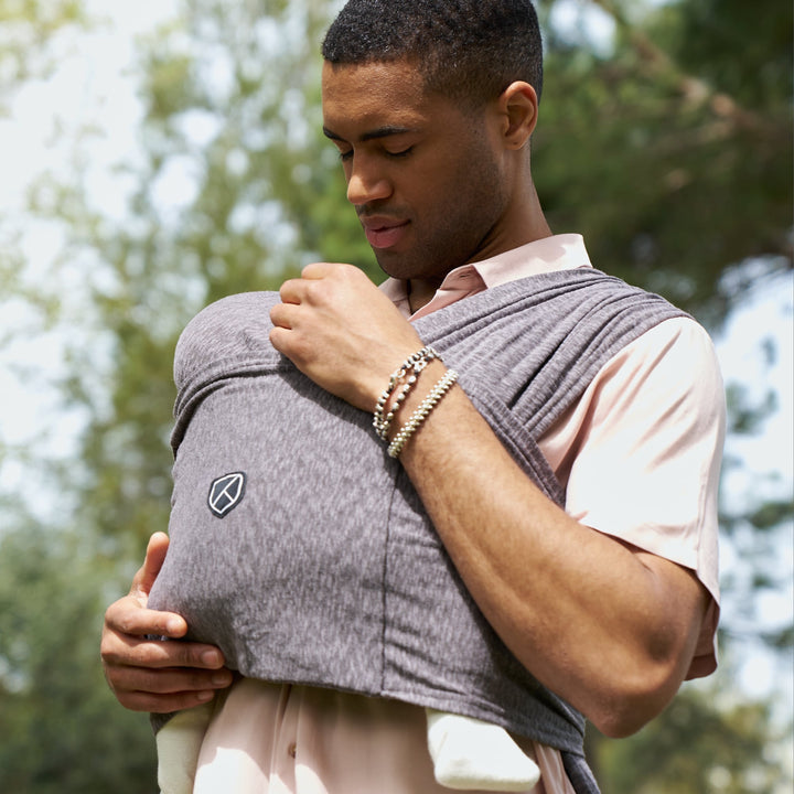 Father using Koala Babycare Koala Cuddle Band in anthracite, ergonomic baby carrier for newborns, outdoors.