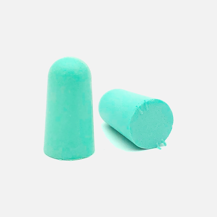 Close-up of Mack's Original Soft Foam Earplugs, teal color, showing tapered design for comfort and noise reduction.