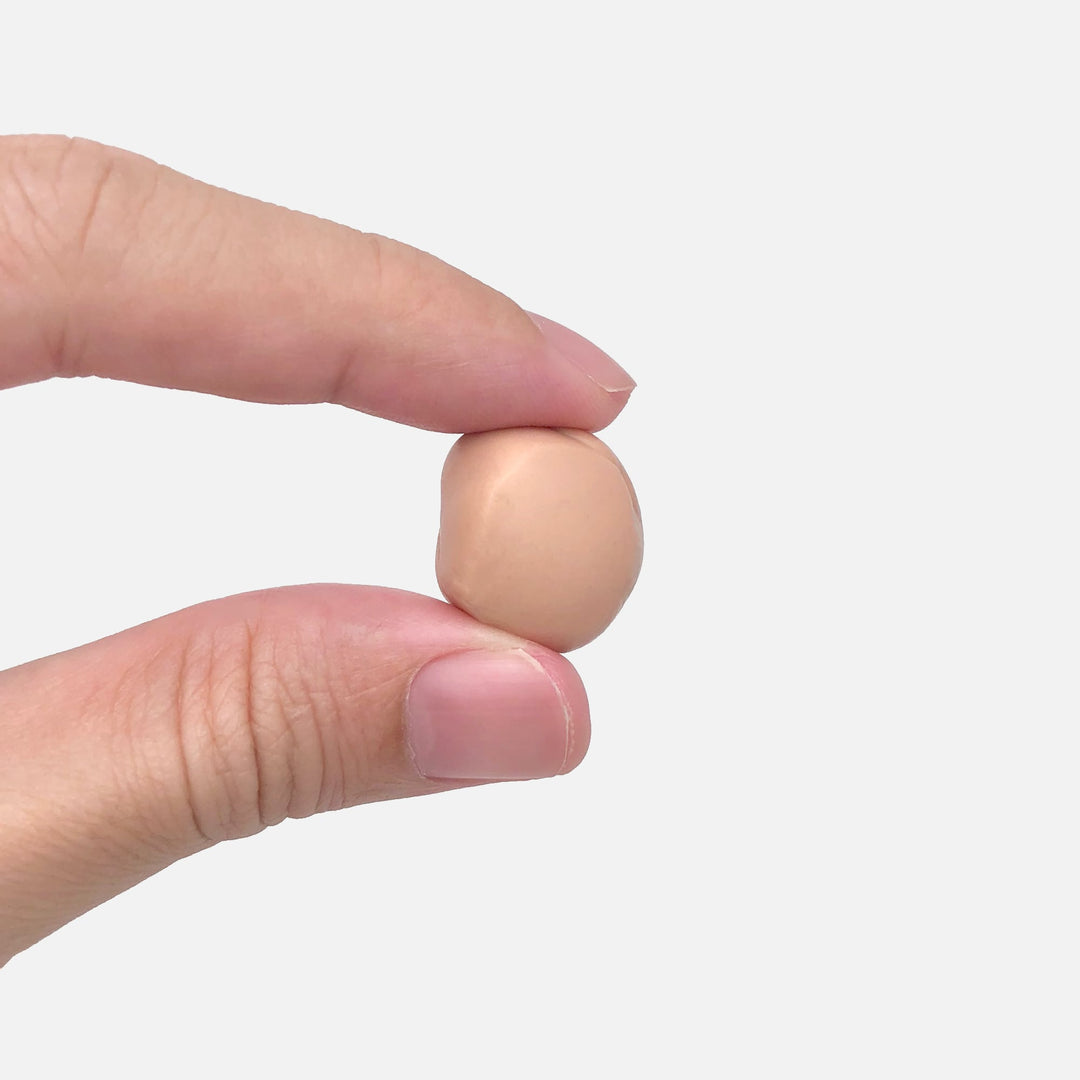 Close-up of a hand holding a moldable Mack's Silicone Earplug, shaped into a ball for custom fit.