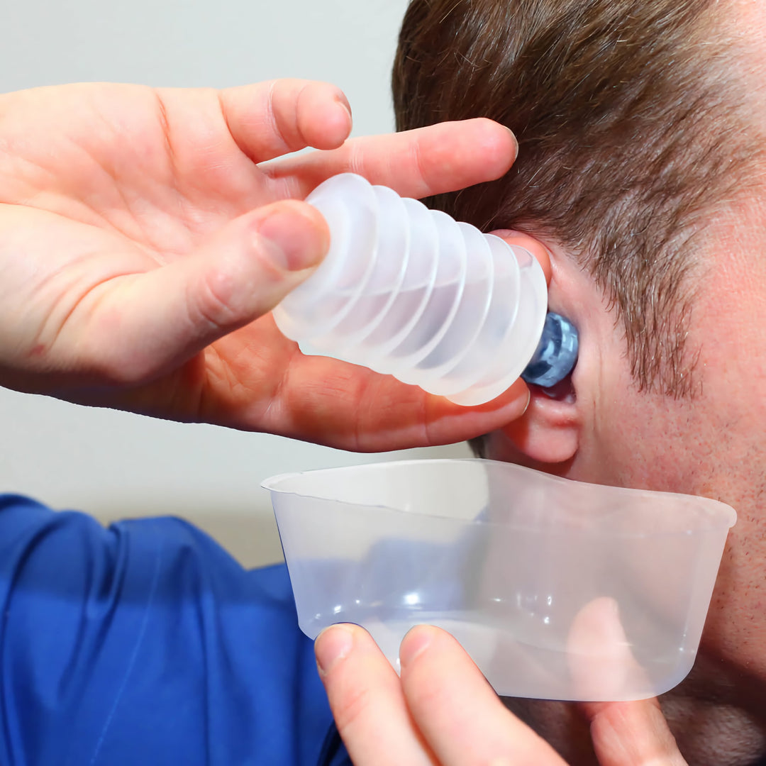 Person using Mack's ProRinse syringe to flush earwax with water draining into catch basin