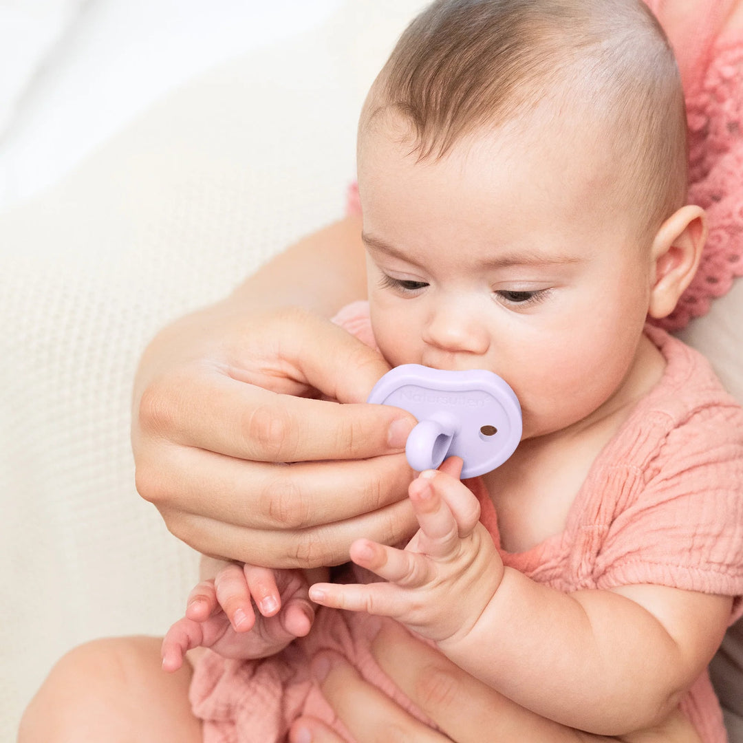 Baby using Natursutten Butterfly Orthodontic Pacifier in Lavender Dreams, held by a parent for soothing comfort.